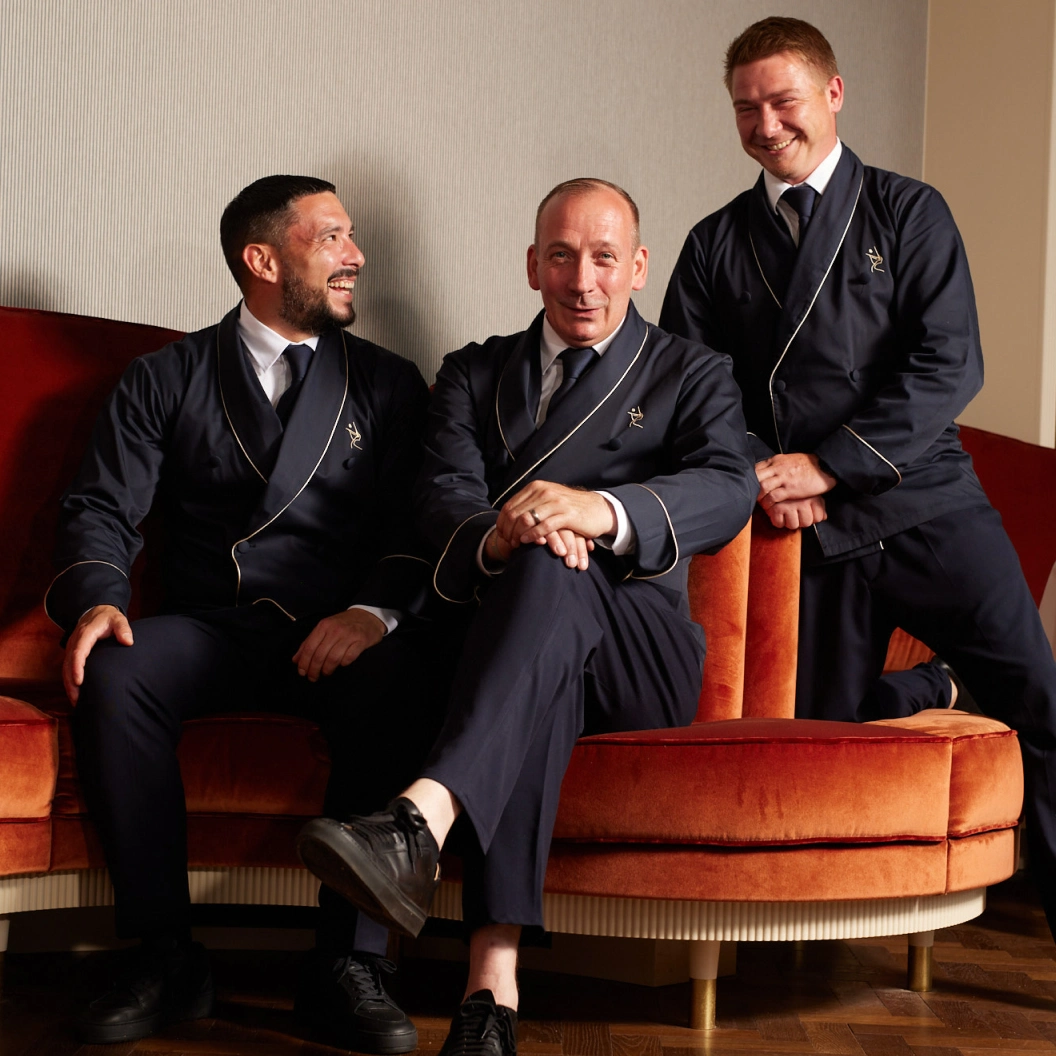Team des Restaurant Pellicano München in eleganter Uniform auf Samtsofa